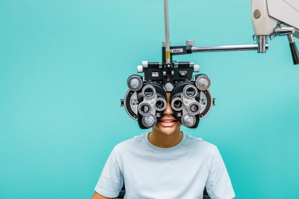 Child sitting behind the phoropter during a kids eye exam
