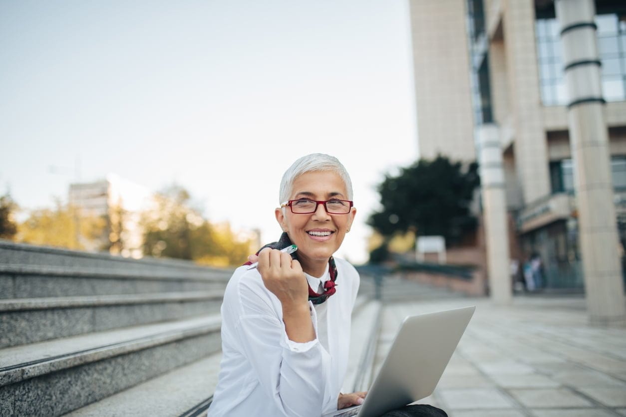 Mature woman sitting outdoors with her computer