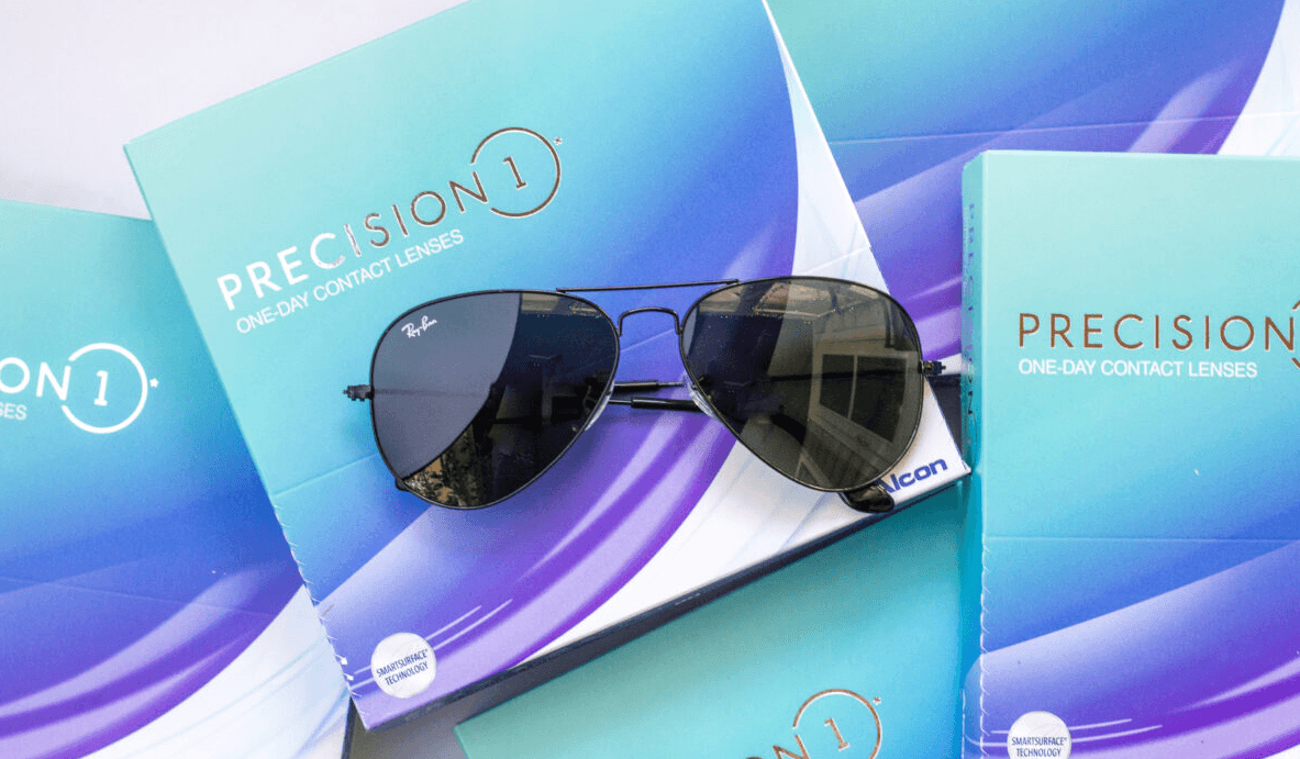 multiple boxes of Precision 1 daily disposable contact lens boxes with a pair of Ray Ban aviator sunglasses on top.