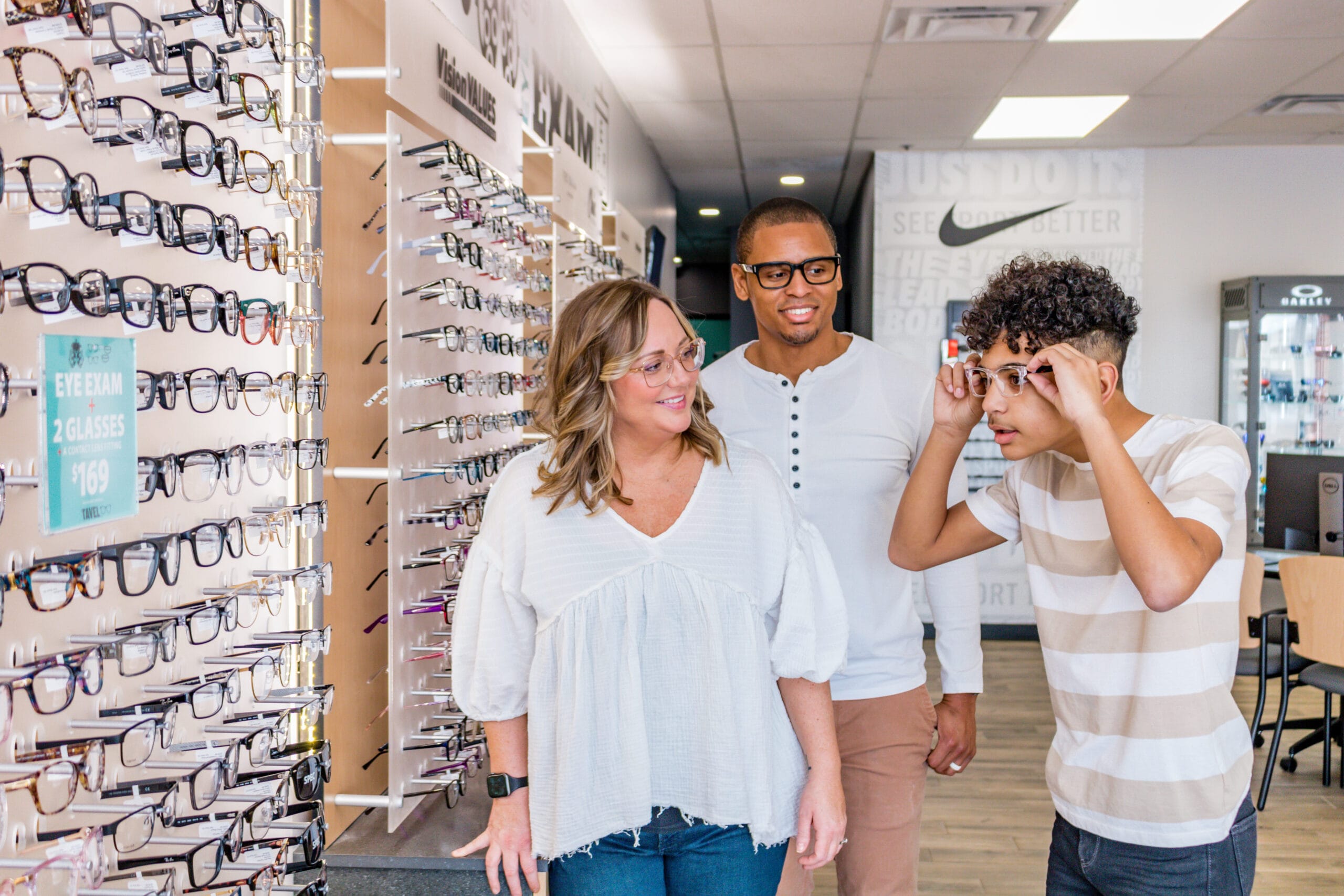 son tries on glasses at a Dr. Tavel office while parents observe